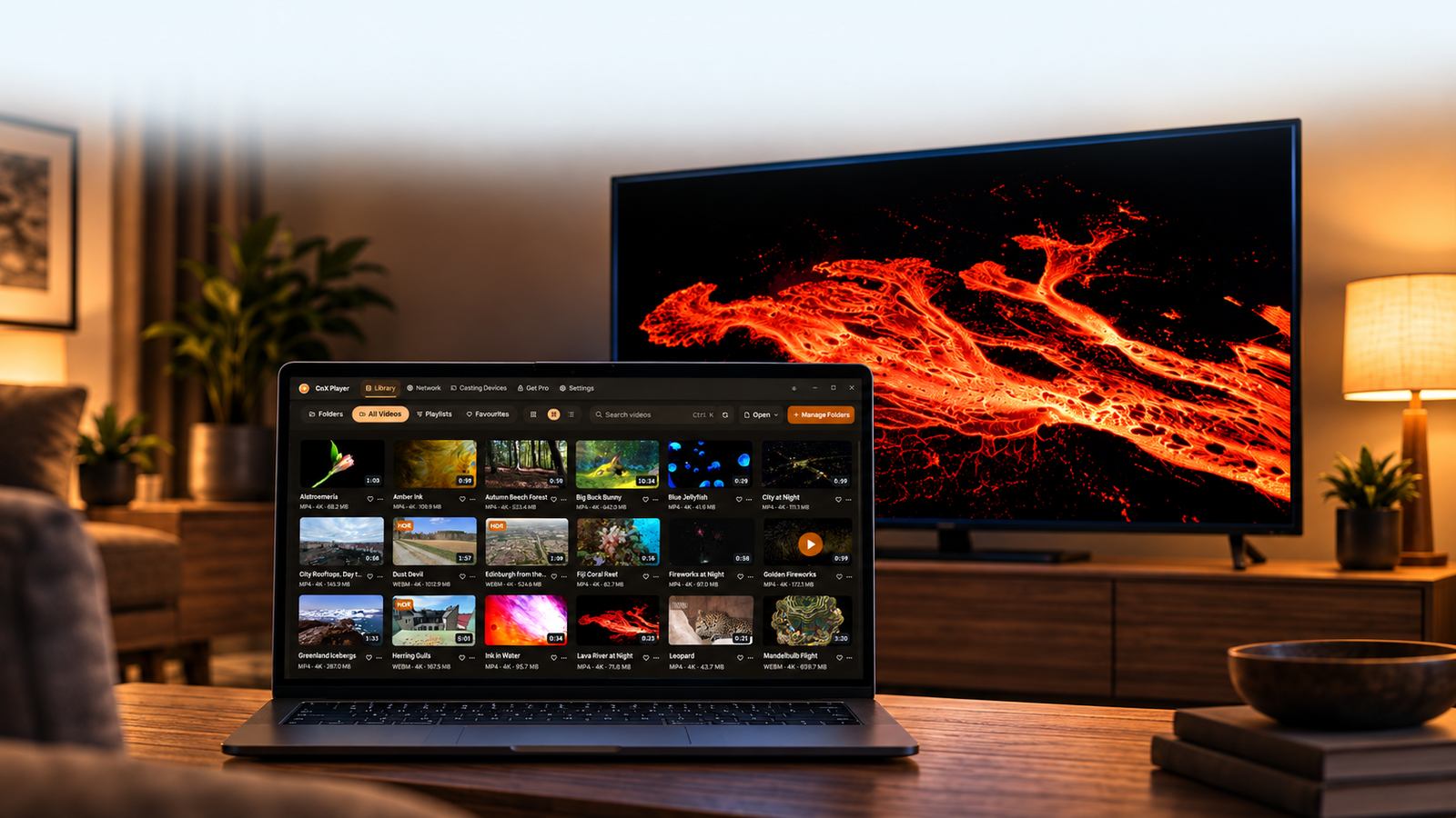 A laptop showing the CnX video library beside a TV showing a lava flow in a warm living room.